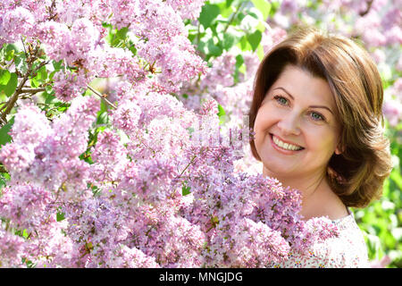 Femme souriante dans alilac jardin au printemps Banque D'Images