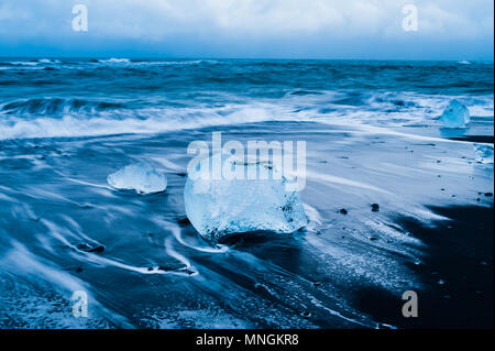 Rochers de glace baignées par la prochaine surf de l'océan Atlantique à sable volcanique noir à diamond beach, l'Islande avril 2018 Banque D'Images