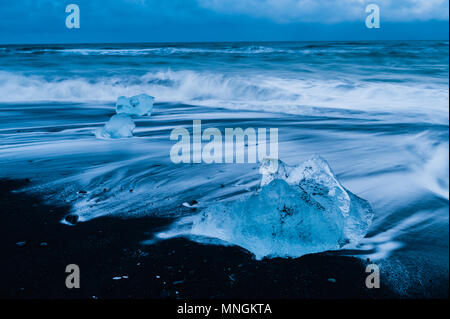 Rochers de glace baignées par la prochaine surf de l'océan Atlantique à sable volcanique noir à diamond beach, l'Islande avril 2018 Banque D'Images