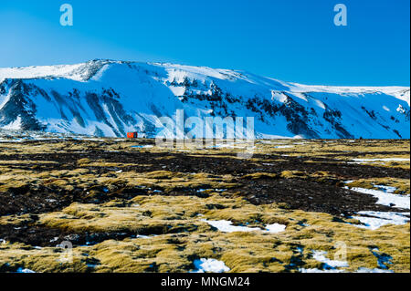 En cabine orange solitaire paysage désolé en face de montagnes couvertes de neige, de l'Islande avril 2018 Banque D'Images