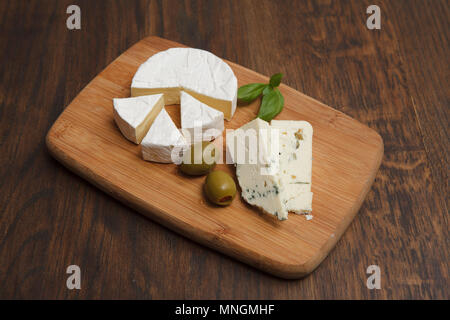 Le camembert avec deux olives sur planche de bois Banque D'Images