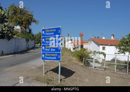 Panneau routier avec des noms de villes de l'anglais et les langues grecque et le sens de la circulation sur l'île de Rhodes (Grèce). Banque D'Images