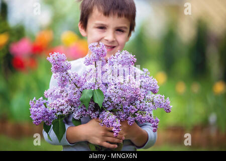 Mon petit enfant, garçon, holding vase avec fleurs lilas en jardin, présent pour maman pour la fête des Mères Banque D'Images