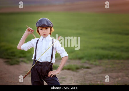 Portrait d'enfant jouant avec arc et flèches, tir à l'arc au tire une cible sur le coucher du soleil Banque D'Images