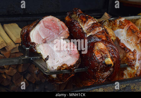 Close up plusieurs gros morceaux de jambon de porc en rotation de la viande d'être uniformément grillés sur feu de bois ouvert brochette, high angle view Banque D'Images