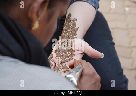 Un artiste à l'henné Shilparamam arts and crafts village, Hyderabad, Inde, l'application de pâte mehndi sur le côté gauche d'une touriste. L'art et la diversité. Banque D'Images