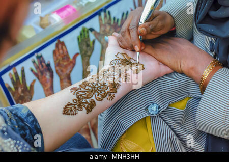 Un artiste à l'henné Shilparamam arts and crafts village, Hyderabad, Inde, l'application de pâte mehndi sur le côté gauche d'une touriste. L'art et la diversité. Banque D'Images