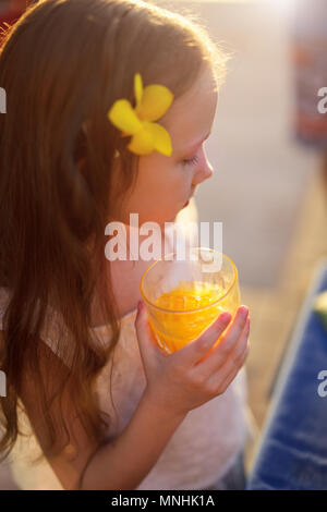 Adorable petite fille boire du jus dans un verre Banque D'Images
