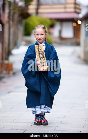 Adorable little girl wearing yukata kimono traditionnel japonais à rue d'une ville de villégiature onsen au Japon. Banque D'Images