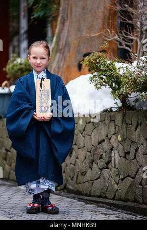 Adorable little girl wearing yukata kimono traditionnel japonais à rue d'une ville de villégiature onsen au Japon Aller à la spa. Banque D'Images