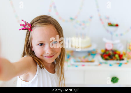 Adorable petite fille princesse avec couronne à kids Birthday party prendre selfies Banque D'Images