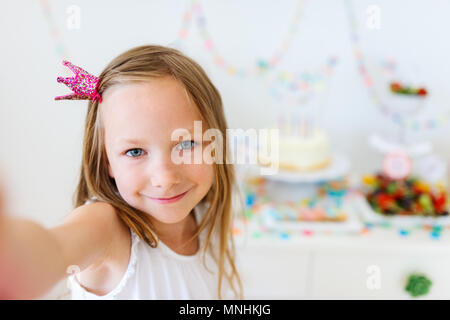 Adorable petite fille princesse avec couronne à kids Birthday party prendre selfies Banque D'Images