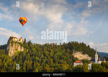 Hot Air Balloon volant sous ciel bleu avec des nuages sur le château et la forêt, Bled, Haute-Carniole, Slovénie Banque D'Images