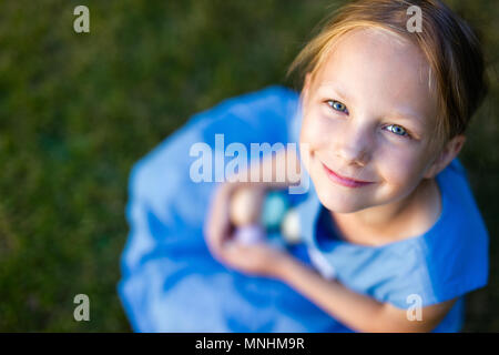 Voir ci-dessus de l'adorable petite fille jouant avec les oeufs de Pâques colorés à l'extérieur sur une pelouse au printemps Banque D'Images