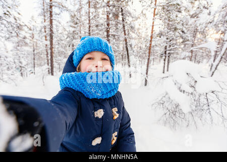 Adorable petite fille portant des vêtements chauds en plein air sur la belle neige d'hiver prendre selfies Banque D'Images