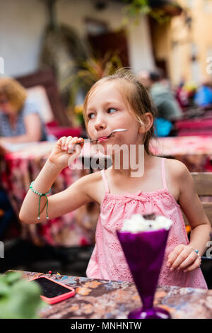 Adorable petite fille dans le café en plein air eating ice cream on summer day Banque D'Images