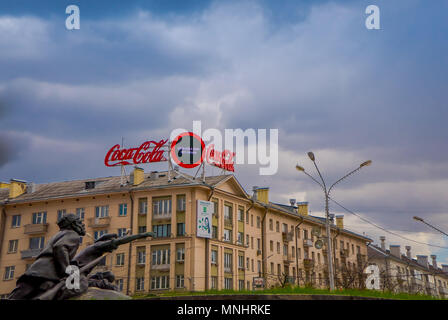 Biélorussie, MINSK - 01 MAI 2018 : monument en bronze en l'honneur du poète national situé dans la région de Yakub Kolas Square, de l'architecture urbaine avec un immeuble d'angle avec coca cola logo dans le toit Banque D'Images