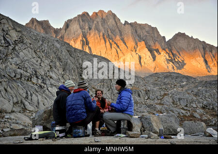 Backpackers d'avoir un dîner avec les projecteurs assis au camp sur les lacs du bassin de Barrett palissade sur un trek de deux semaines de la Haute Sierra Itinéraire dans le Parc National Kings Canyon en Californie. La route de 200 milles environ en parallèle avec le John Muir Trail populaire à travers la Sierra Nevada de Californie Plage de Kings Canyon National Park Le Parc National de Yosemite. Coucher du soleil illumine la palissade du nord dans l'arrière-plan. Banque D'Images