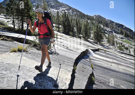 Randonnée à travers un backpacker plaque de granit sur le sentier du col de l'évêque de bassin Dusy en Canyon Le Conte sur un trek de deux semaines de la Haute Route Sierra en Kings Canyon National Park en Californie. La route de 200 milles environ en parallèle avec le John Muir Trail populaire à travers la Sierra Nevada de Californie Plage de Kings Canyon National Park Le Parc National de Yosemite. Banque D'Images