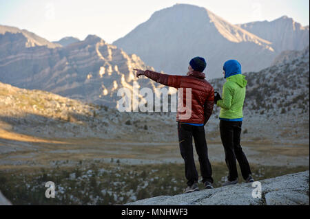 Un couple regarde le lever du soleil sur les montagnes du bassin du lac de marionnettes sur un trek de deux semaines de la Haute Route dans la Sierra John Muir Wilderness en Californie. La route de 200 milles environ en parallèle avec le John Muir Trail populaire à travers la Sierra Nevada de Californie Plage de Kings Canyon National Park Le Parc National de Yosemite. Banque D'Images