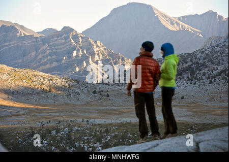 Un couple regarde le lever du soleil sur les montagnes du bassin du lac de marionnettes sur un trek de deux semaines de la Haute Route dans la Sierra John Muir Wilderness en Californie. La route de 200 milles environ en parallèle avec le John Muir Trail populaire à travers la Sierra Nevada de Californie Plage de Kings Canyon National Park Le Parc National de Yosemite. Banque D'Images