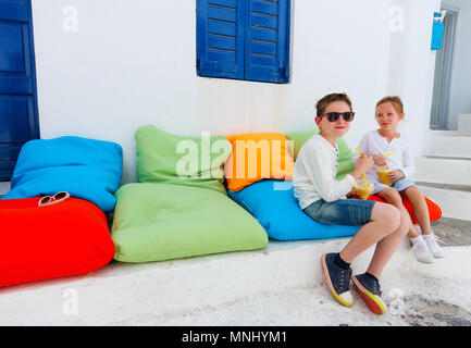 Mignon deux enfants frère et sœur de boire des smoothies frais sur un des oreillers colorés au café en plein air sur la journée d'été Banque D'Images