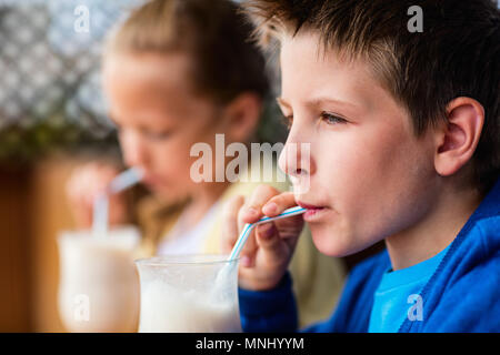 Les jeunes frère et sœur de lait frappé au café en plein air potable Banque D'Images