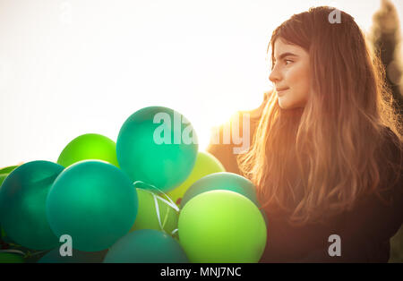 Portrait of a cute girl en plein air avec grand tas de ballons verts, prépare à célébrer anniversaire, heureux de l'enfance insouciante Banque D'Images