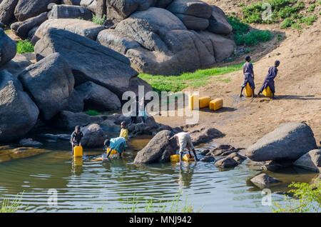 Les jeunes enfants non identifiés du remplissage des conteneurs d'eau à fleuve jaune Banque D'Images