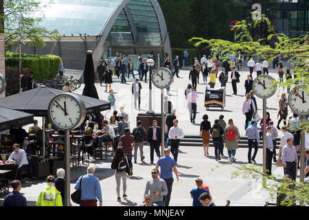 Canary Wharf, horloges indiquent le moment juste avant 12h à l'extérieur de la station de métro avec les employés autour de la mouture le soleil brille, Banque D'Images