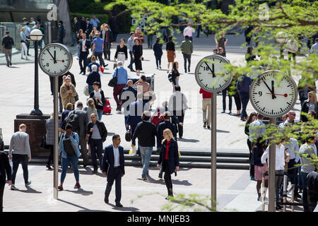Canary Wharf, horloges indiquent le moment juste avant 12h à l'extérieur de la station de métro avec les employés autour de la mouture le soleil brille, Banque D'Images