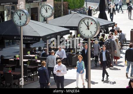 Canary Wharf, horloges indiquent le moment juste avant 12h à l'extérieur de la station de métro avec les employés autour de la mouture le soleil brille, Banque D'Images