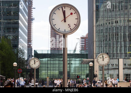 Canary Wharf, horloges indiquent le moment juste avant 12h à l'extérieur de la station de métro avec les employés autour de la mouture le soleil brille, Banque D'Images