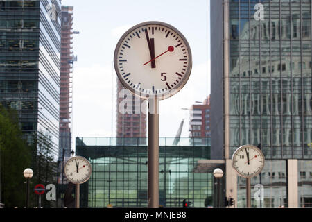 Canary Wharf, horloges indiquent le moment juste avant 12h à l'extérieur de la station de métro avec les employés autour de la mouture le soleil brille, Banque D'Images