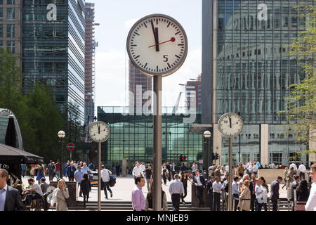 Canary Wharf, horloges indiquent le moment juste avant 12h à l'extérieur de la station de métro avec les employés autour de la mouture le soleil brille, Banque D'Images