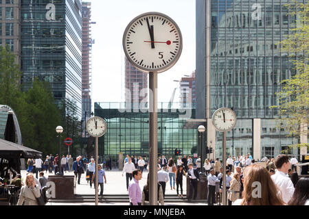 Canary Wharf, horloges indiquent le moment juste avant 12h à l'extérieur de la station de métro avec les employés autour de la mouture le soleil brille, Banque D'Images