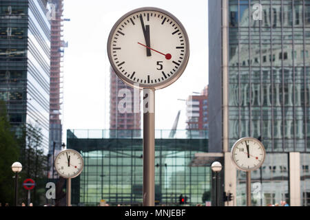Canary Wharf, horloges indiquent le moment juste avant 12h à l'extérieur de la station de métro avec les employés autour de la mouture le soleil brille, Banque D'Images