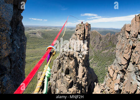 Deux jeunes grimpeurs gréement jusqu'highline entre deux hautes falaises rocheuses, Tasmanie, Australie Banque D'Images