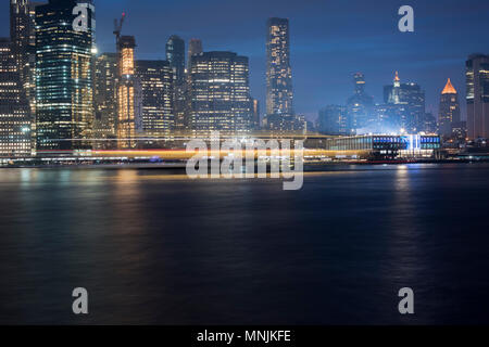 Une longue exposition de Mai 2018 Manhattan avec sentiers de lumière le trafic des ferries, et la nouvelle jetée 17 bâtiment à droite. Banque D'Images