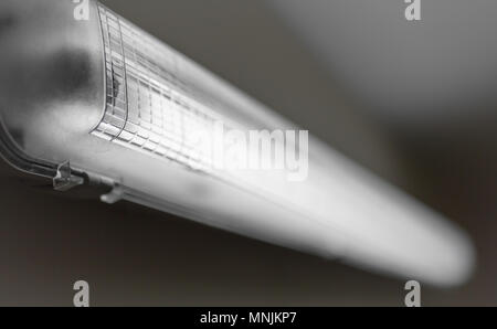 Vieille lampe néon s'allume, avec faible lumière, un mur de béton. Focus sélectif. Arrière-plan flou flou artistique. Banque D'Images