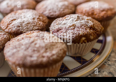 Lot de petits gâteaux faits maison ou des muffins fraîchement cuits au four de refroidissement sur une plaque décorée, dans la cuisine dans une vue en gros plan avec focus sélectif. Banque D'Images