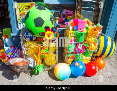 Couleurs vives ou des ballons de plage de couleur pour la vente sur le trottoir ou à l'extérieur d'un sentier boutique, avec seau en plastique et chat. Banque D'Images