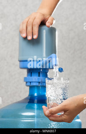 Mains de femme versant de l'eau de la bouteille avec une pompe Banque D'Images