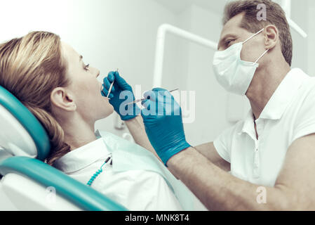 Friendly dentiste contrôler les dents de devant de son patient Banque D'Images