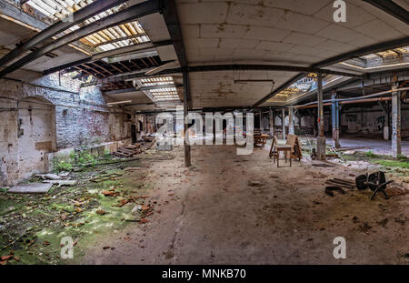 Hall désert d'une usine destinée à la ruine. Les rayons de lumière sont de brillants à travers les fenêtres brisées Banque D'Images