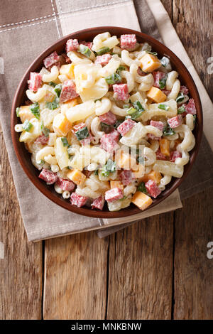 Nourriture hawaïenne : salade de pâtes, jambon, ananas, oignons, fromage cheddar, close-up avec de la mayonnaise dans un bol sur la table. Haut Vertical Vue de dessus Banque D'Images