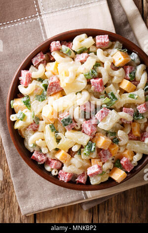 Salade de pâtes avec Hawaiian copieux, jambon, ananas, oignons, fromage cheddar habillés avec de la mayonnaise close-up dans un bol sur la table. Vue supérieure verticale fro Banque D'Images