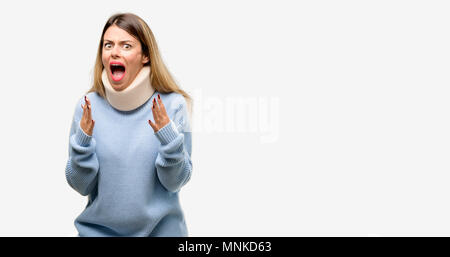 Jeune femme blessée wearing neck brace collar stressant en gardant les mains sur la tête, terrifié, criant en panique Banque D'Images