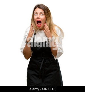 Propriétaire de boutique woman wearing apron stressant en gardant les mains sur la tête, terrifié, criant en panique Banque D'Images