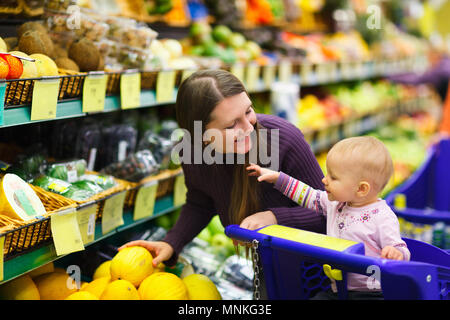 Mère et sa petite fille à l'achat de fruits et légumes de supermarché Banque D'Images